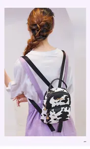 Rear view of model wearing a stylish mini cow print backpack with adjustable black straps