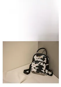 Close-up of the black and white cow print synthetic leather texture and golden metal logo