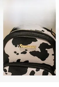 Close-up of cow print textured fabric with golden logo and premium hardware details