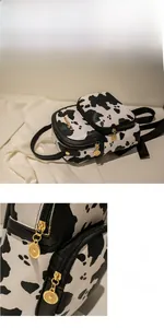 Detail of cow print mini backpack showing the smooth gold metal zipper and PU leather texture