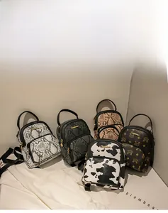 Detail view of mini backpacks in cow print and faux leather textures with gold hardware