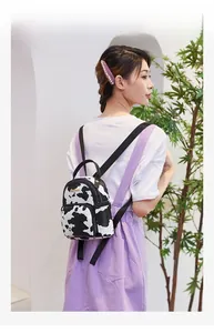Detailed side view of mini cow print backpack being worn by a model in soft light