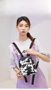 Detailed view of a compact cow print backpack with front zipper pocket and metal logo