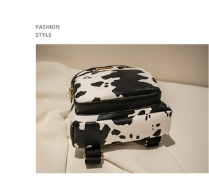 Detail view of mini cow print backpack showing gold zippers and side structure