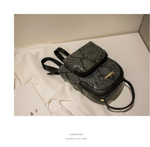 Detail shot of mini backpack with textured snake pattern and gold metal logo accent