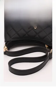 Detailed view of black quilted faux leather bag with butterfly hardware and zipper