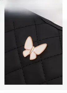 Close-up of quilted black leather with a golden butterfly metal charm and detailed stitching