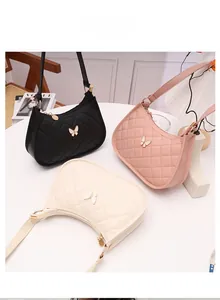 Close-up of three quilted hobo bags in black, pink, and white with butterfly metal charms