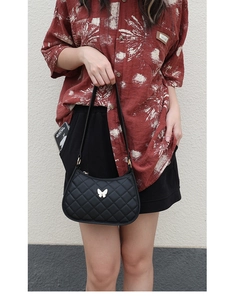 Black quilted shoulder bag with butterfly detail shown on model in street style