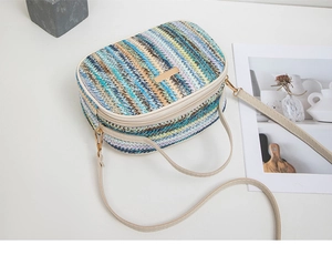Dettaglio della borsa a tracolla intrecciata colorata con finiture dorate e tracolla avorio
