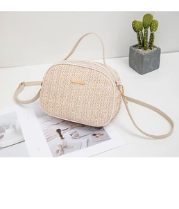 Dettaglio borsa a tracolla in paglia intrecciata beige con placca dorata e zip di chiusura