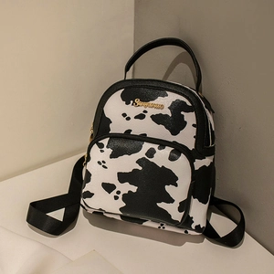 Mini cow print backpack in PU leather with gold logo and dual straps on neutral background