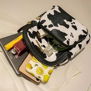 Chic cow print mini crossbody bag with gold hardware and daily makeup essentials