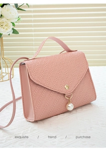 Detailed view of pink woven texture phone bag with large pearl charm and gold hardware