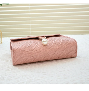 Detail of pink woven crossbody bag featuring a large pearl clasp and elegant texture