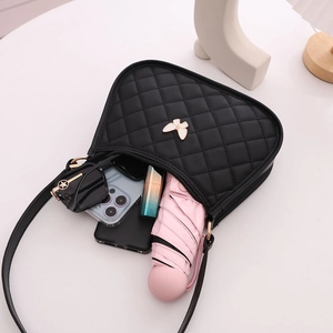 Black quilted crescent shoulder bag with butterfly detail and daily essentials layout