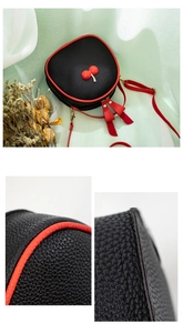Detail of lychee textured leather and red stitched edges on a mini cherry crossbody bag