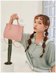 Pink faux crocodile leather handbag held by model in a stylish indoor setting