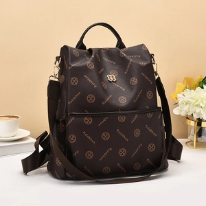 Brown leather backpack with floral prints and gold logo on a desk with lifestyle props