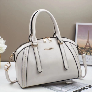 Weiße Retro Boston Handtasche mit goldenen Beschlägen und Nieten auf grauem Hintergrund
