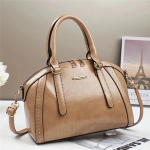 Khaki Boston pillow bag with golden studs and detachable strap in a minimalist setting