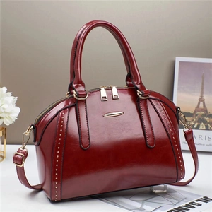 Detail of vintage burgundy leather handbag with gold rivets and metallic accents