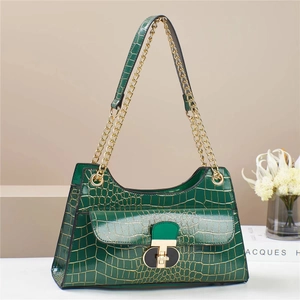 Detail of dark green crocodile texture handbag with gold metal lock and leather strap