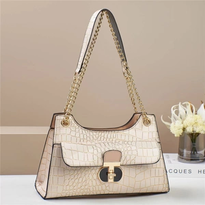 Detail of beige crocodile pattern handbag featuring a chic gold and black metal buckle lock