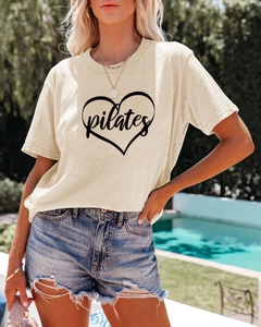 Outdoor view of an oat-colored Pilates t-shirt featuring a heart graphic and crew neck