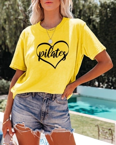 Close-up of bright yellow Pilates heart t-shirt with soft cotton texture in sunlight