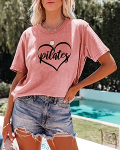Detail of pink Pilates heart print T-shirt paired with ripped denim shorts by the pool