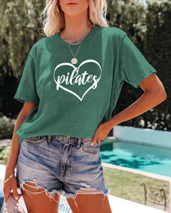 Outdoor shot of a casual dark green Pilates heart t-shirt paired with denim shorts
