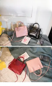 Detail of crocodile pattern small square bags in pink, black, and red colors