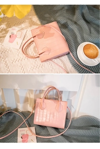 Detailed top view of a pink crocodile texture handbag on a soft knitted blanket