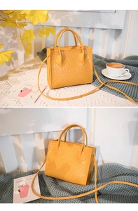 Macro view of bright yellow crocodile pattern handbag on aesthetic fabric texture