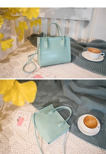 Detail of mint green crocodile pattern handbag with handle and shoulder strap
