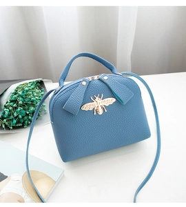 Dettaglio della borsa blu con trama litchi e fibbia a forma di ape in metallo dorato