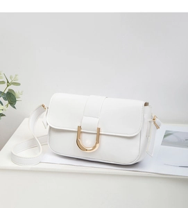 Primer plano de bolso bandolera blanco con hebilla metálica dorada en forma de U pulida