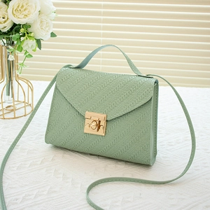 Elegant light green woven crossbody bag with gold rotary clasp on a lace tablecloth