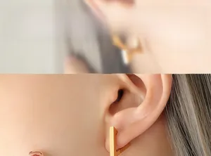 Macro view of geometric V-shaped gold titanium earrings worn by a model