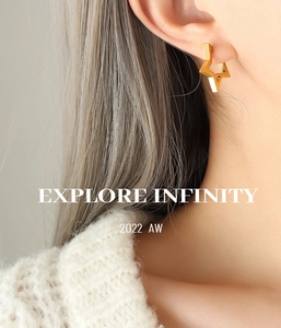 Close-up of a minimalist gold star geometric earring worn with a cozy white sweater