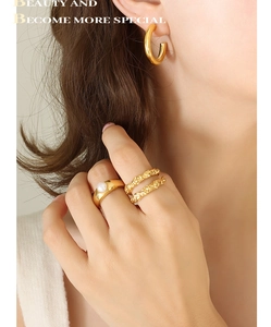 Nahaufnahme von goldenen C-Ohrringen und Perlenring an Model im minimalistischen Stil