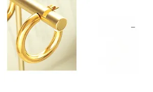 Detailaufnahme von 18K vergoldeten C-förmigen Creolen an einem minimalistischen Schmuckständer