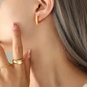 Minimalist geometric gold earrings and pearl ring set shown on a female model
