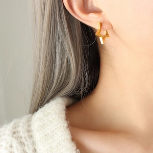 Polished gold star geometric hoop earrings worn by model with warm autumn knitwear