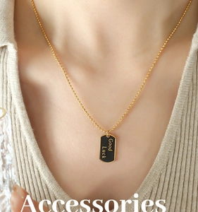 Nahaufnahme der goldenen Kugelkette mit schwarzem Good Luck Anhänger an einem Model