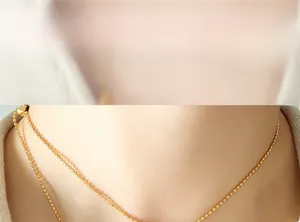Nahaufnahme einer goldenen Kugelhauskette am Hals für einen minimalistischen Stil