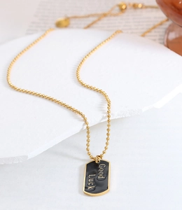 Detail der Goldperlenkette mit schwarzem Emaille-Anhänger und Good Luck Gravur
