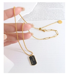 Nahaufnahme der goldenen Kugelkette mit schwarzem rechteckigem Good Luck Anhänger