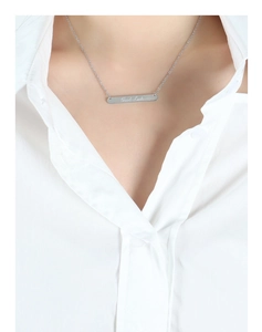 Gros plan sur un pendentif barre argentée polie avec gravure Good Luck pour femme